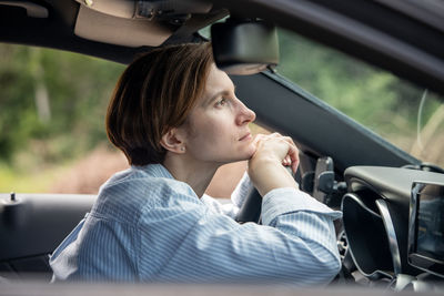 Middle aged frustrated woman driving car having problems on road waiting in traffic jam.