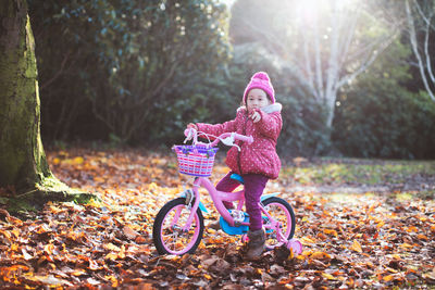 Full length of girl with bicycle standing in park