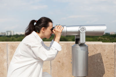 Young woman photographing through binoculars