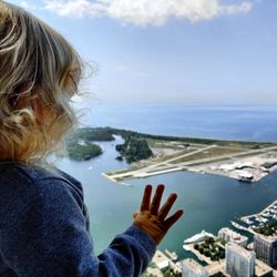 Baby boy looking at sea through glass window