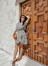 Full length portrait of woman standing against wall