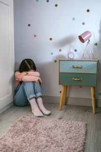 Unrecognizable girl crying on the floor in her bedroom