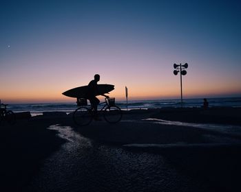 Silhouette man riding bicycle on beach