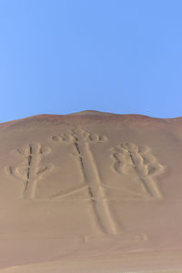 Low angle view of sand dune against clear blue sky