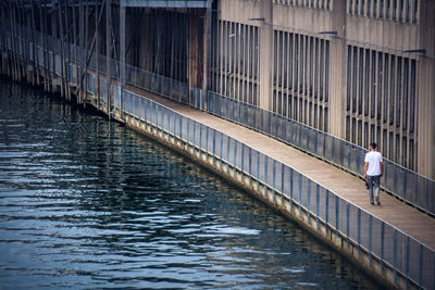 Rear view of mature man walking on footpath by river