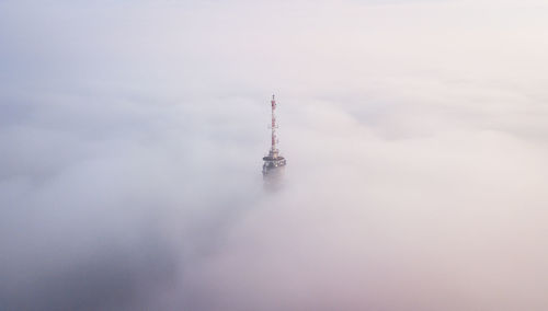 High angle view of communications tower amidst clouds