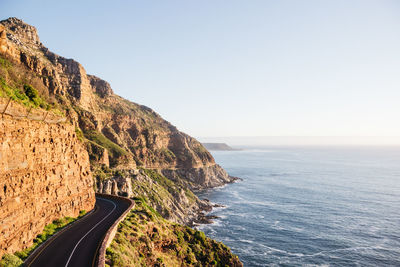 Scenic view of sea by mountains against clear sky