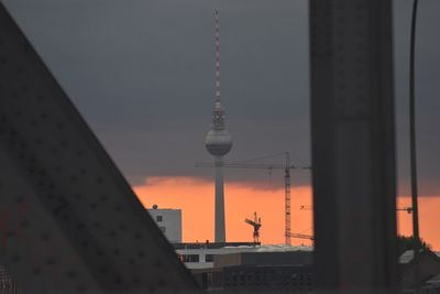 Communications tower in city against sky