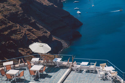 High angle view of chairs and tables with umbrella on building terrace by sea