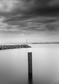 Wooden posts in sea against sky