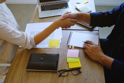 High angle view of business people shaking hands on table