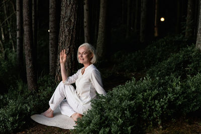 Middle aged woman doing yoga outdoors in forest
