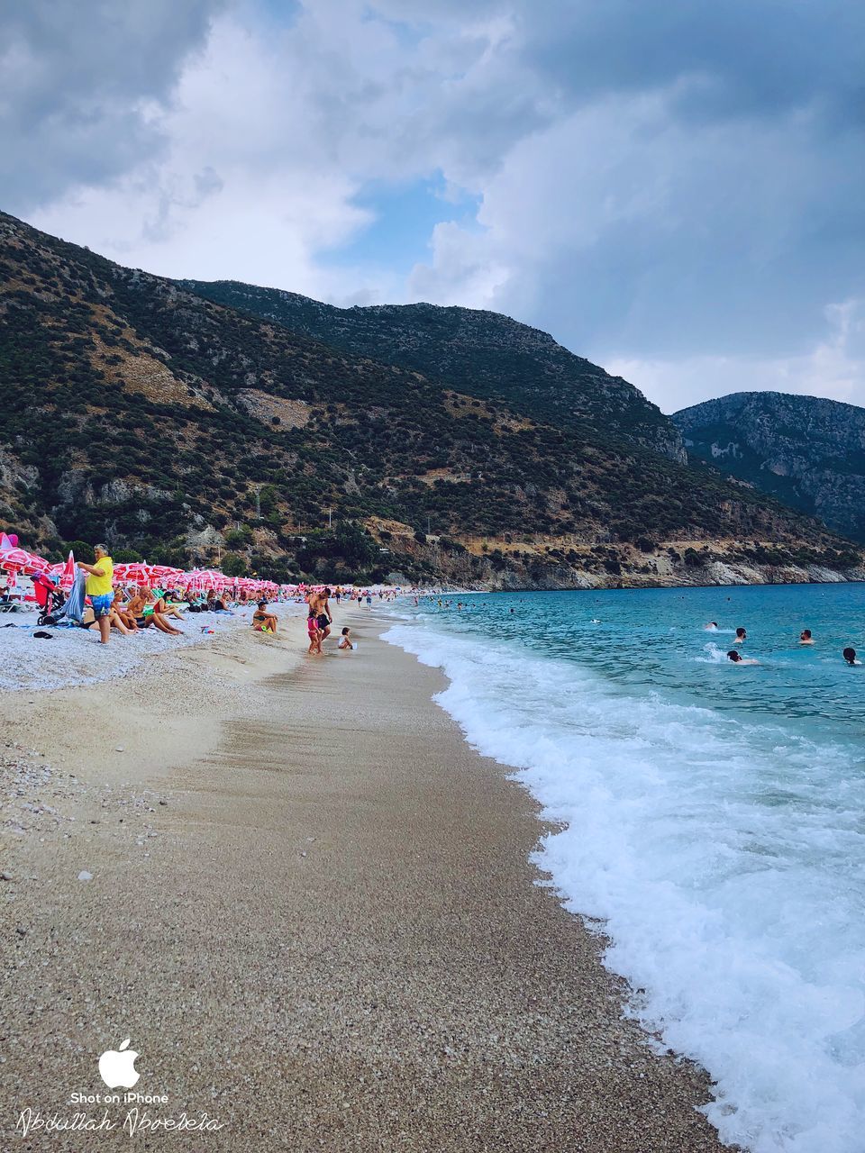 GROUP OF PEOPLE ON BEACH AGAINST MOUNTAINS