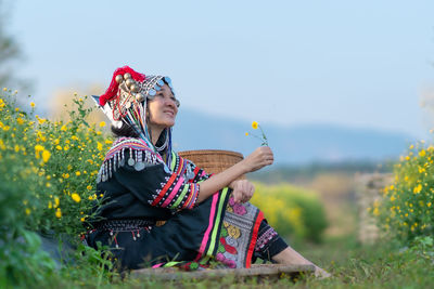 Woman holding umbrella while standing on flowering plants