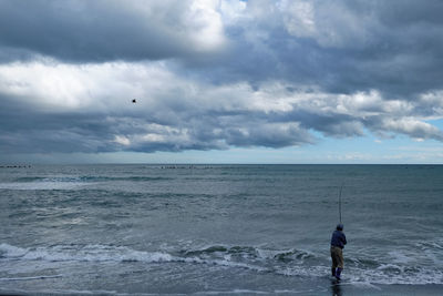 Fisherman fishing in sea at beach