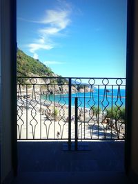 Fence by sea against blue sky seen through window