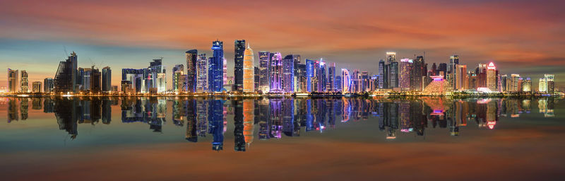 Reflection of illuminated buildings in lake against sky