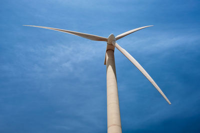 Low angle view of wind turbine against blue sky
