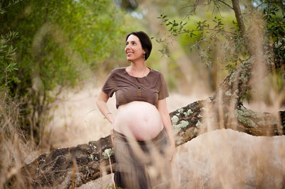 Young woman smiling while standing against trees