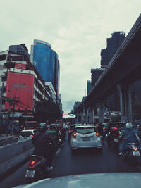 Traffic on road by buildings against sky