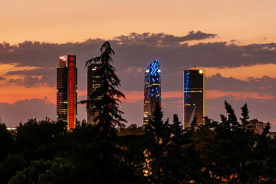Illuminated modern buildings against sky during sunset