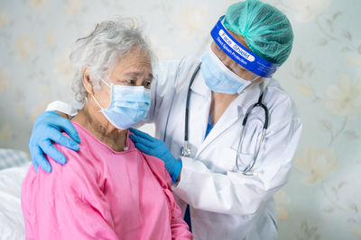 Doctor wearing mask consoling patient at hospital