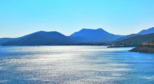 Scenic view of lake and mountains against clear blue sky