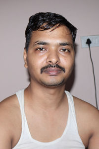 Close-up portrait of smiling young man against wall