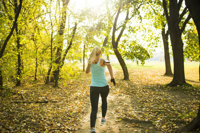 Rear view of woman running in park during autumn