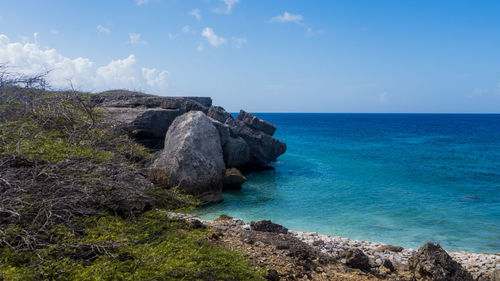 Scenic view of cliff by sea against sky