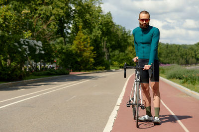 Rear view of man riding bicycle on road