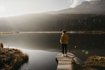 Switzerland, engadine, lake staz, woman standing on a jetty at lakeside in morning sun