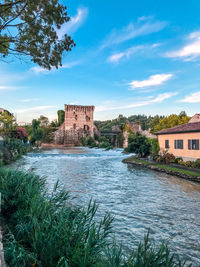 View of old building by river against sky