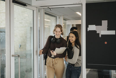 Happy student with friend entering classroom in university