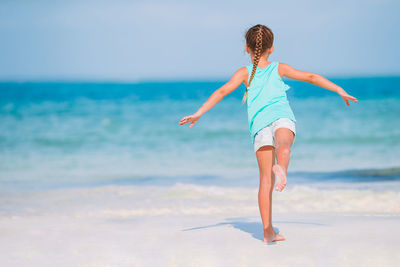 Rear view of woman walking on beach against sky