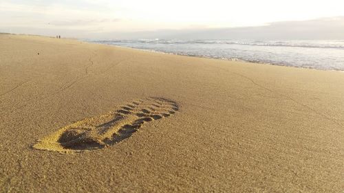 High angle view of footprints on sand at beach against sky