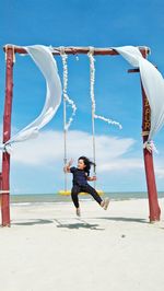 Girl gesturing peace sign on swing at beach