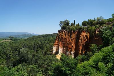 Ocher rock formations on landscape against clear blue sky