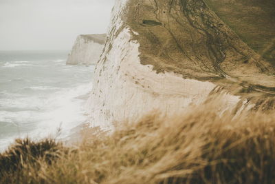 Scenic view of sea and cliff against sky