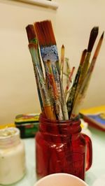 Close-up of paintbrushes in jars on table