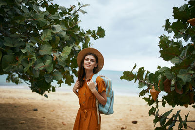 Portrait of young woman standing against plants