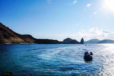 People on boat sailing in sea during sunny day