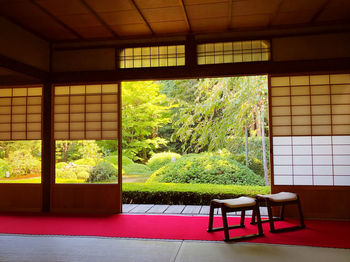 Empty chairs and table against window in building