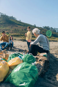 Rear view of people sitting on land against clear sky