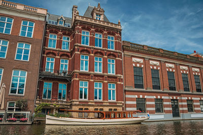 Boat moored on canal and brick buildings in amsterdam. the netherland capital full of canals.