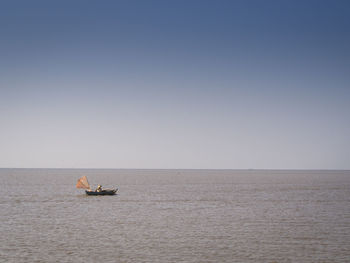 Boat sailing on sea against clear sky