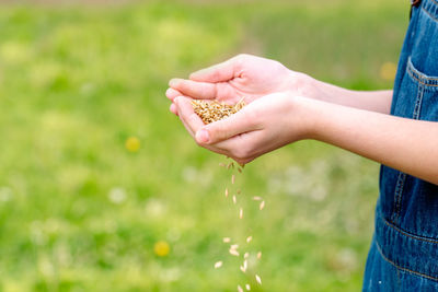 Midsection of woman holding hands on field