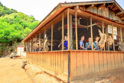 People standing outside house against sky