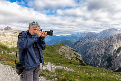 Man photographing on mountain against sky