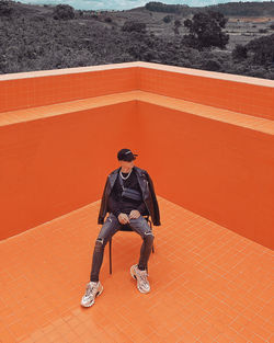 Full length of man standing against orange wall